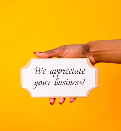 A hand holding a sign with 'We appreciate your business!' against a yellow background.